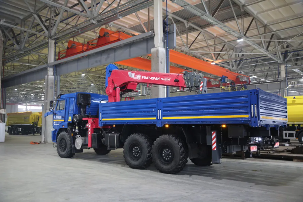 Синий грузовик с красным краном в цеху